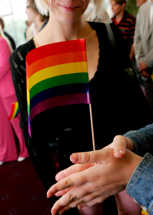 two people hold a small rainbow flag together