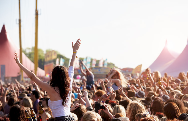 A girl raises her arms in the crowd at a music festival in San Francisco