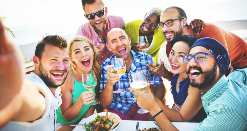 A group of young people having wine by the water