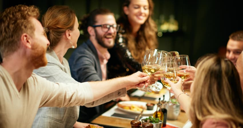 A group of people toasting wine at a dining table