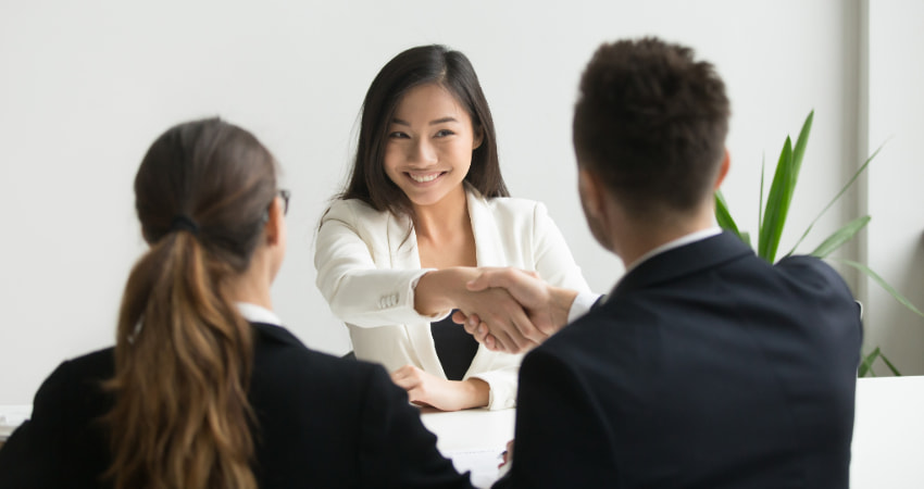 A woman shakes hands with a potential employer after a successful interview