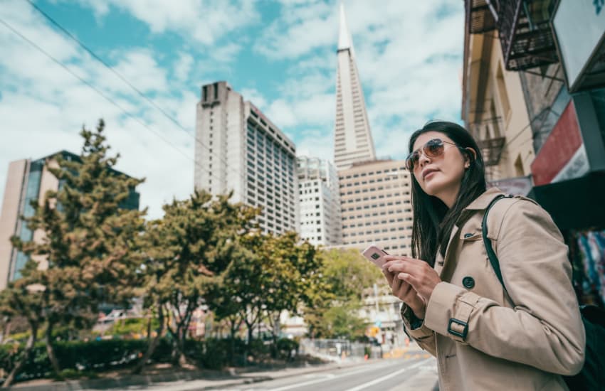 A woman stands on a corner in San Francisco, waiting for the bus