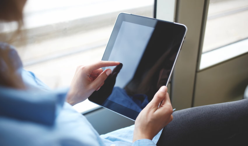 a woman uses a mobile tablet device while riding on a bus