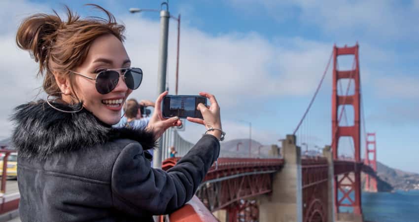 A woman taking a selfie photo while walking the golden gate bridge