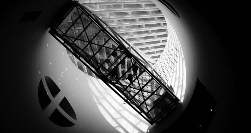 A black and white photo looking up at a suspended walkway inside the San Francisco Museum of Modern Art