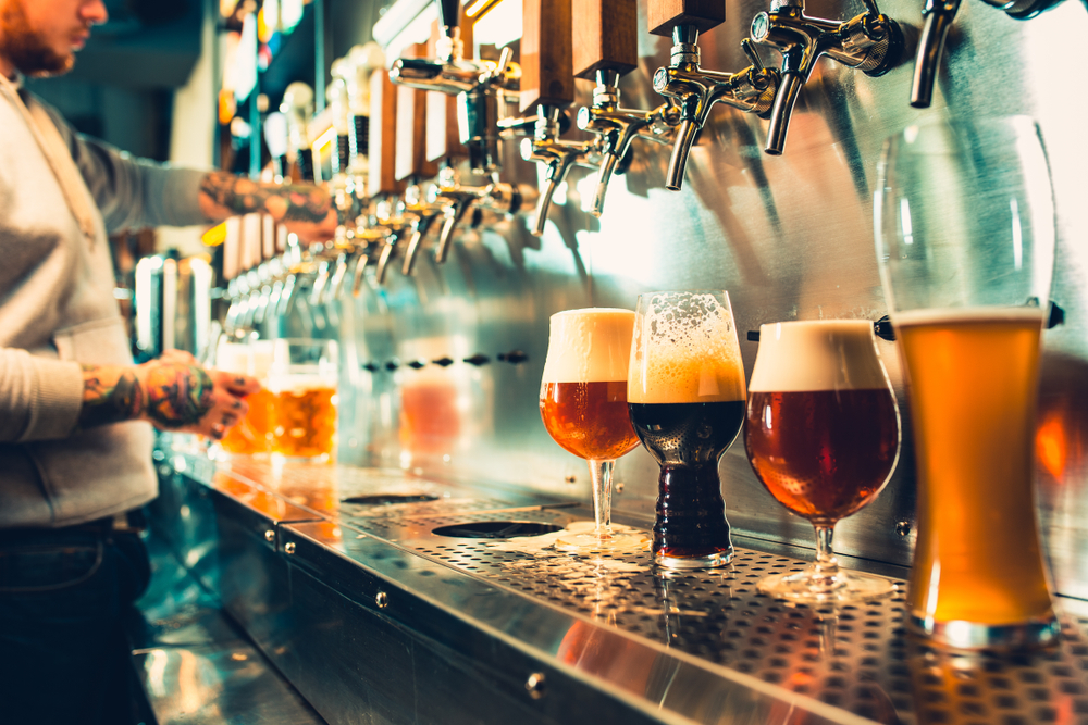 Bartender pouring beers into lined-up glasses