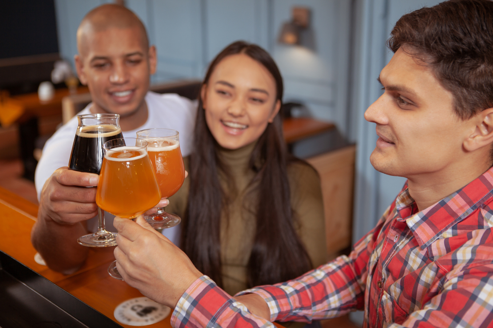 Friends clinking glasses of beer at bar