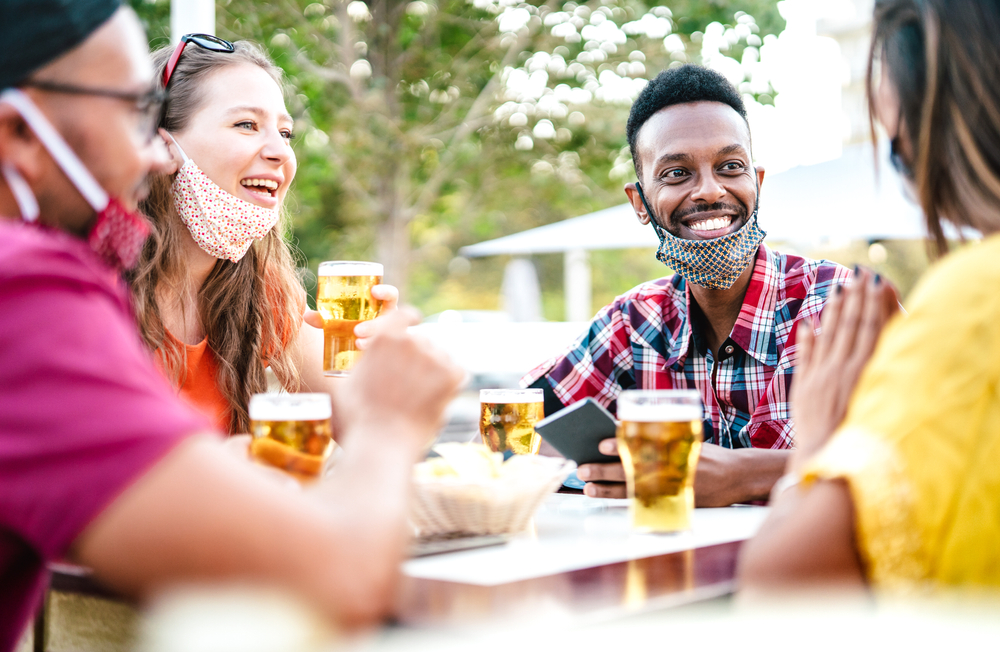 Friends drinking outside with masks lowered