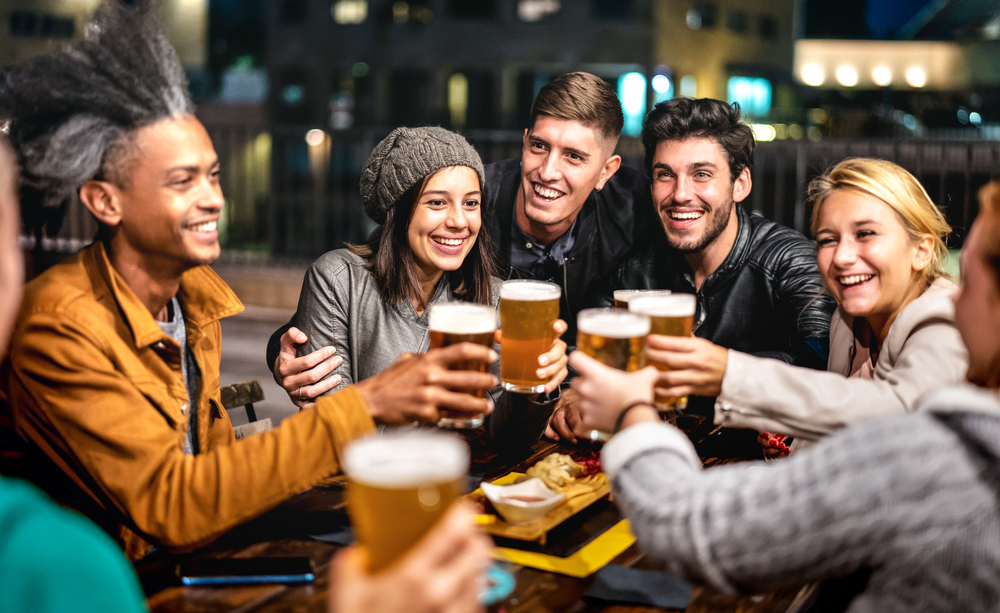 Friends toasting with beer outside of bar