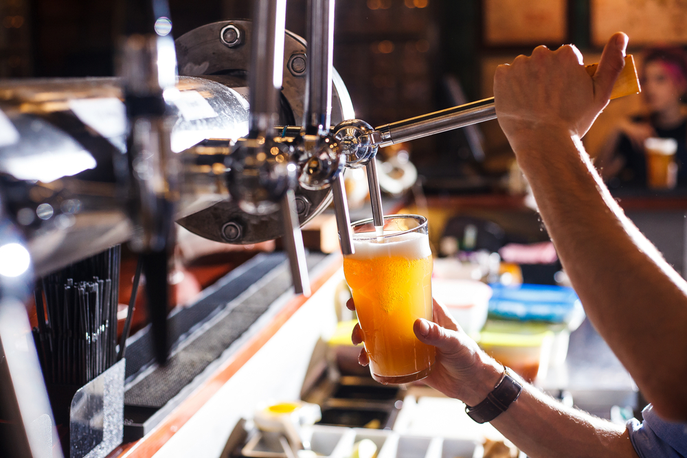 A bartender pours beer from a tap