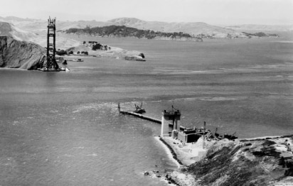 A black and white photo from 1932 as the Golden Gate Bridge is being constructed across the bay