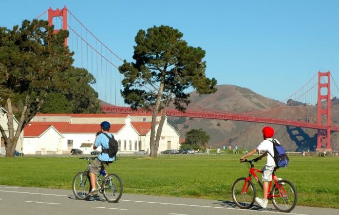 Two bikers ride past a viewpoint of the Golden Gate Bridge in the Presidio