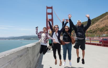 A group of friends jumping and smiling in front of the Golden Gate Bridge