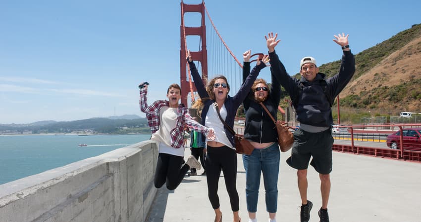 A group of friends jumping and smiling in front of the Golden Gate Bridge