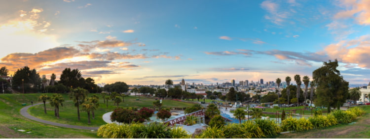 an aerial view of mission dolores park, with lots of green space, trees, and the city buildings in the background