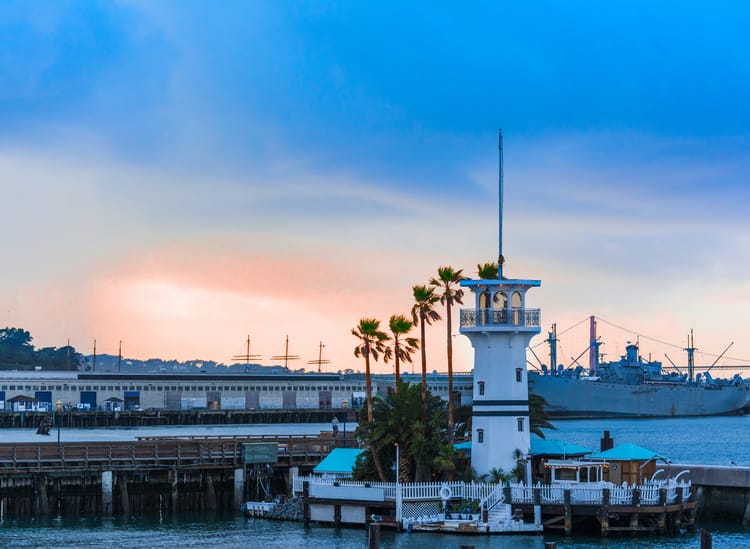 a lighthouse stands over the water at dusk