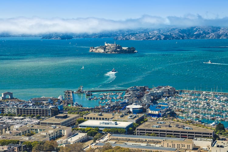 an aerial view of fisherman's wharf with alcatraz and mountains in the distance