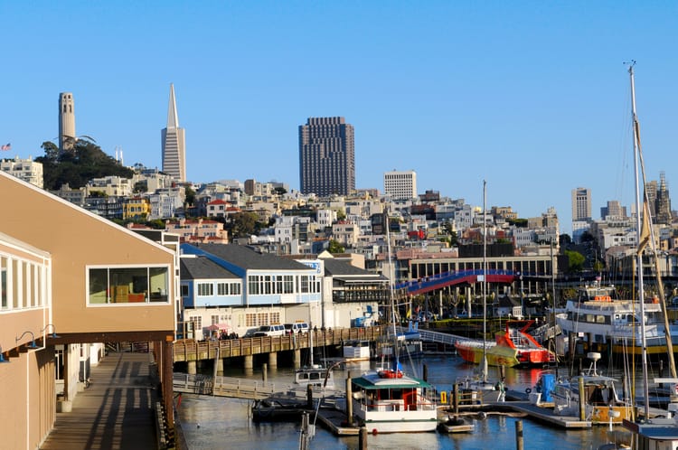 pier 39 at fisherman's wharf, with buildings on stilts int he water and the city in the background