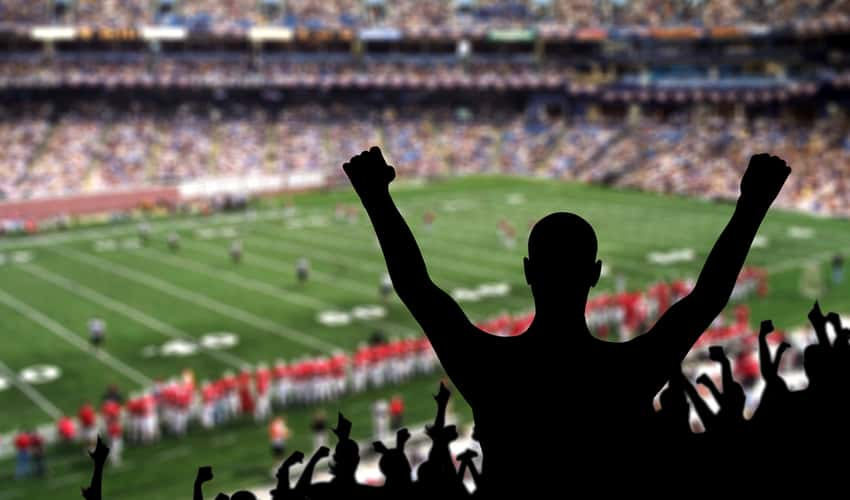 Fans cheering in a football stadium at a college game