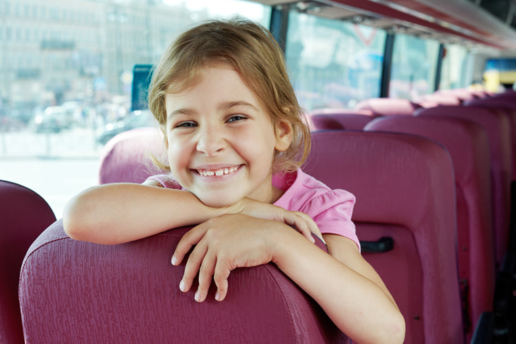 young girl smiling aboard a charter bus rental