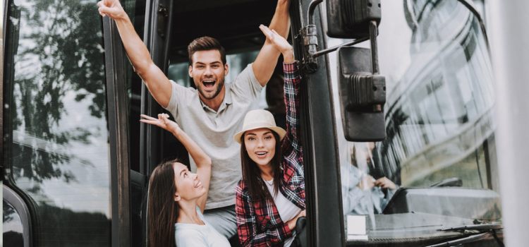 three friends in front of a charter bus