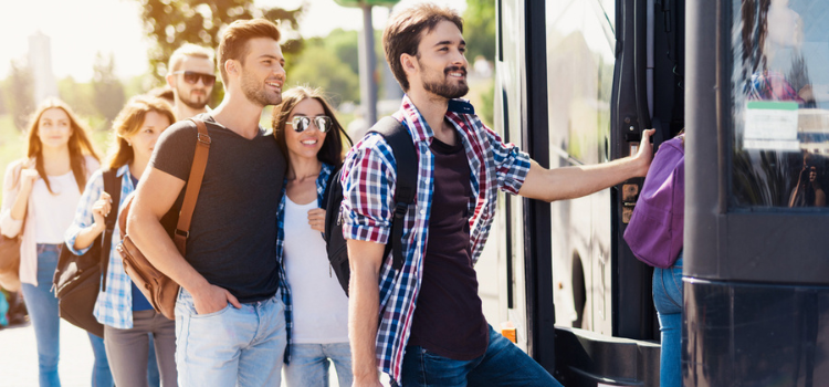 a group of people with luggage step aboard a charter bus